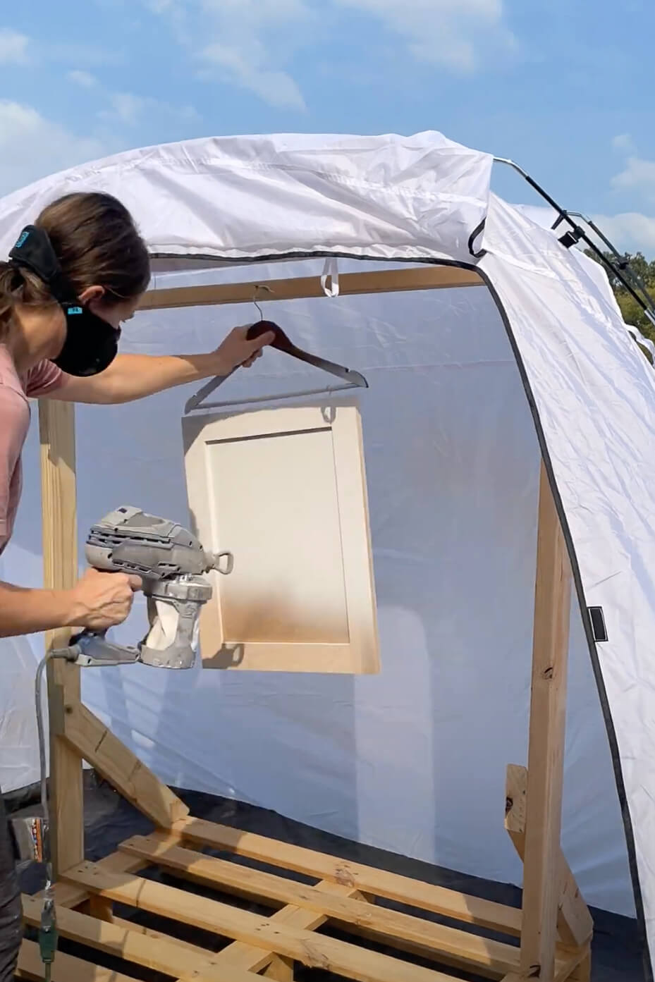 Painting kitchen cabinets with a paint sprayer.